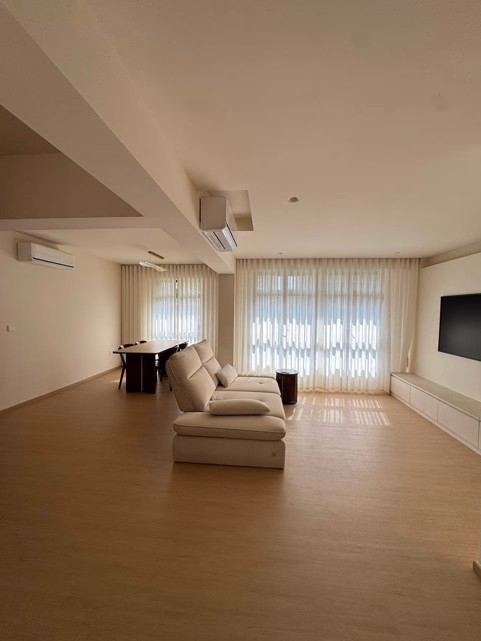 Sheer white day curtains across full-height windows in an open-plan Singapore condominium living and dining room