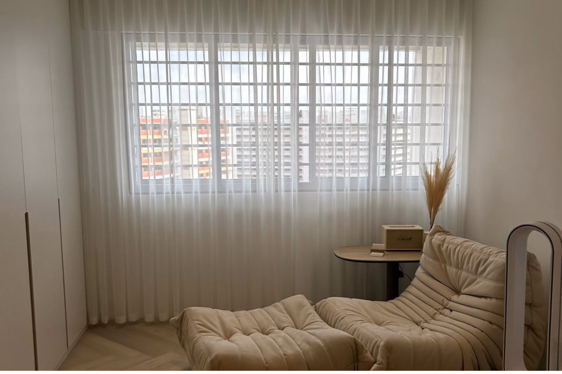 Sheer white day curtains softening the light across a wide Singapore HDB bedroom window